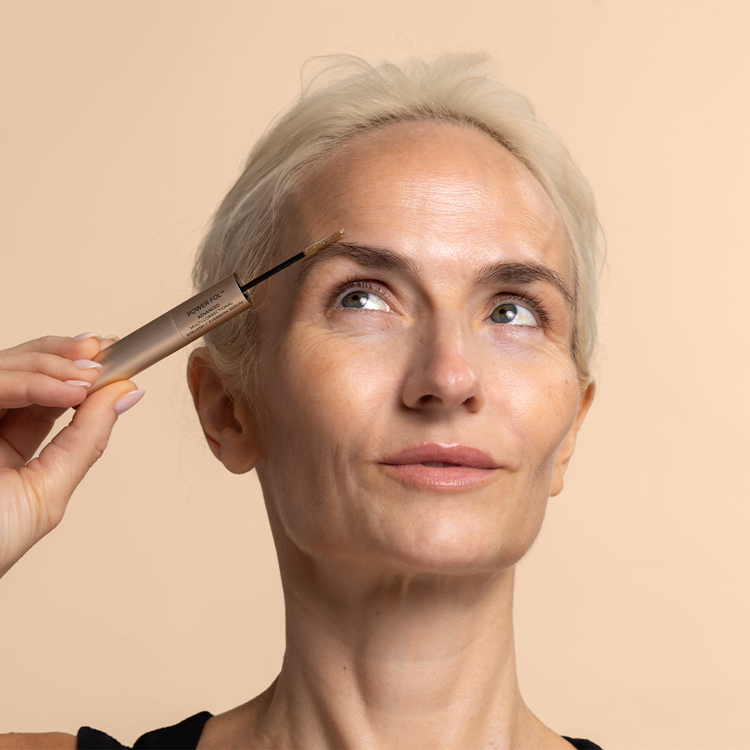 Maya Chia | PowerFol Lash & Brow | Model Image_Sep26 - person applying lash & brow serum to eyebrow against a peach background