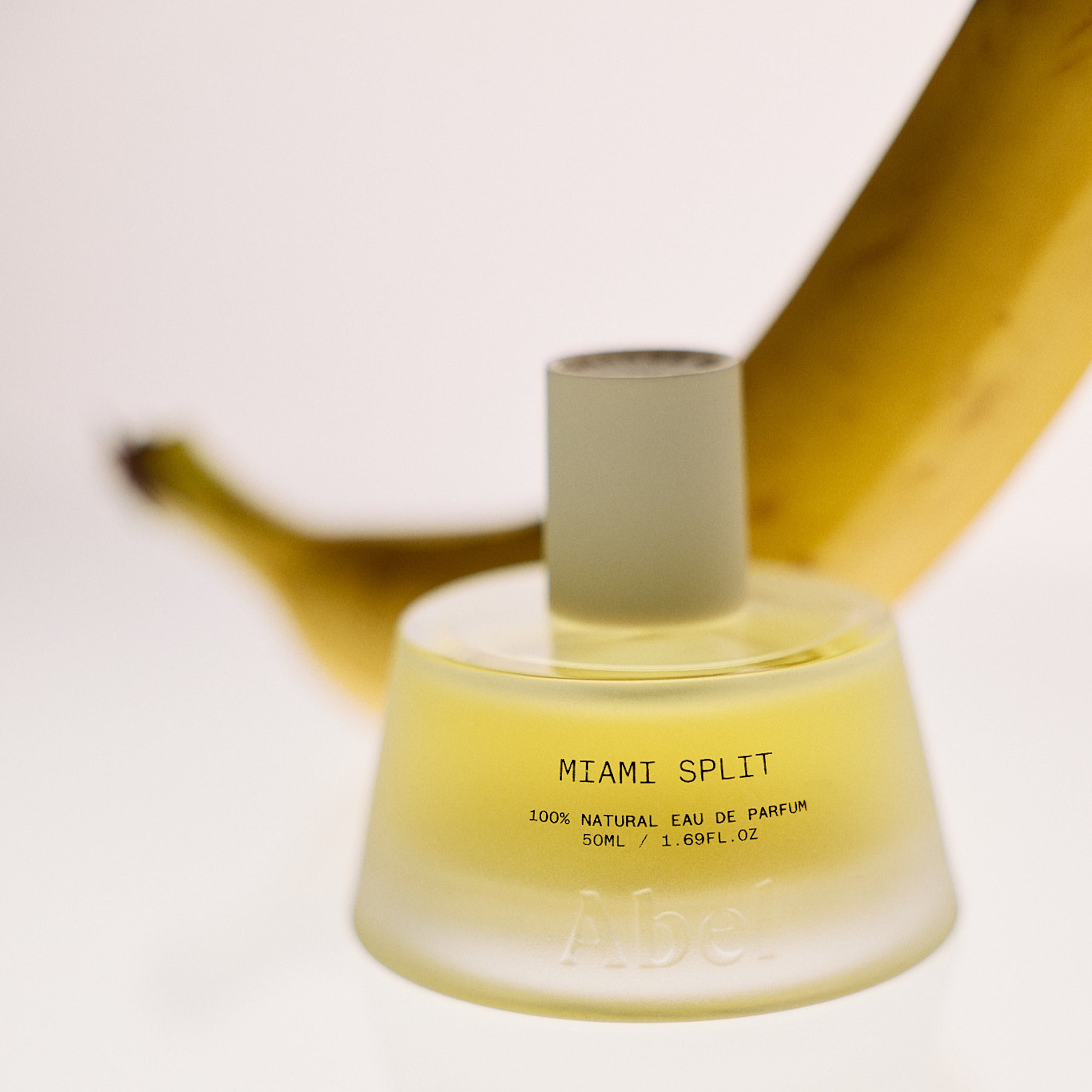 Abel | Miami Split Eau De Parfum | Glass bottle with white top on white background with banana in the background 