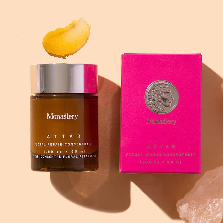 Monastery | Attar Floral Repair Concentrate | Styled image with swatch, dark bottle with silver cap alongside bright pink product box with yellow balm swatch