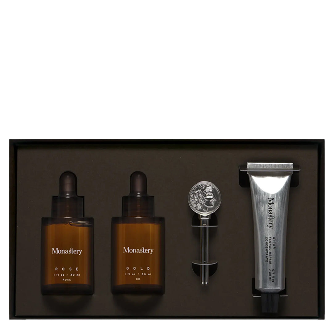 Monastery | Essentials Kit | Product Image - skincare set with Rose and Gold oils, Attar Floral Repair Concentrate, and Monastery coin logo key in a black presentation box