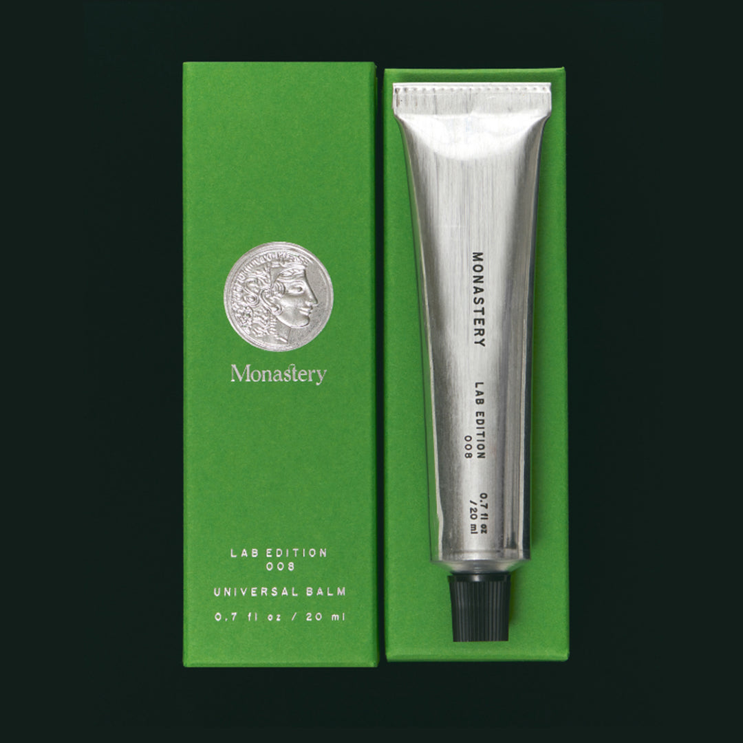 Monastery | Universal Balm | Packaging Image - silver tube and green packaging on a dark background