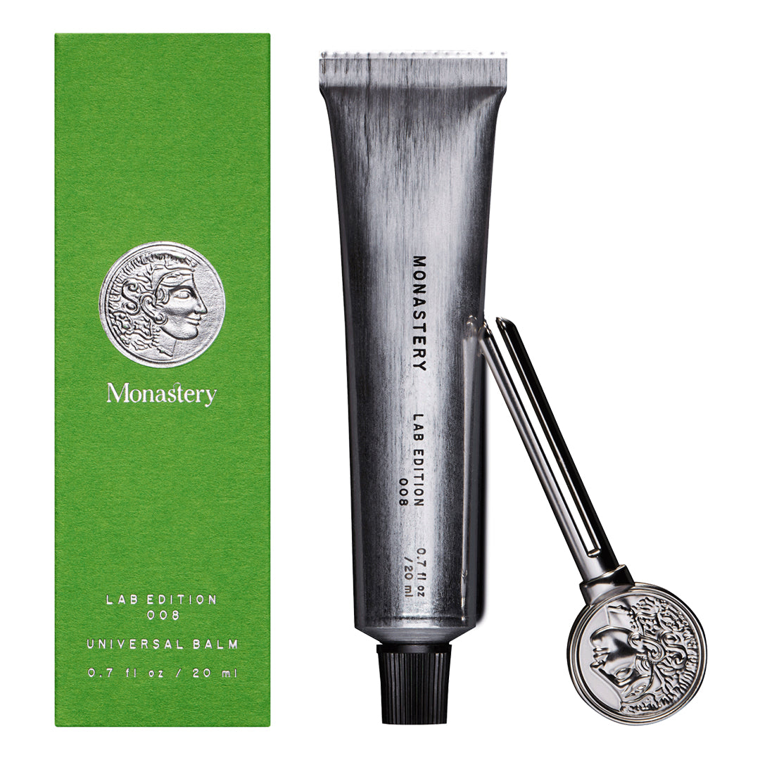 Monastery | Universal Balm | Packaging Image2 - silver tube, green packaging and  coin logo key on a white background