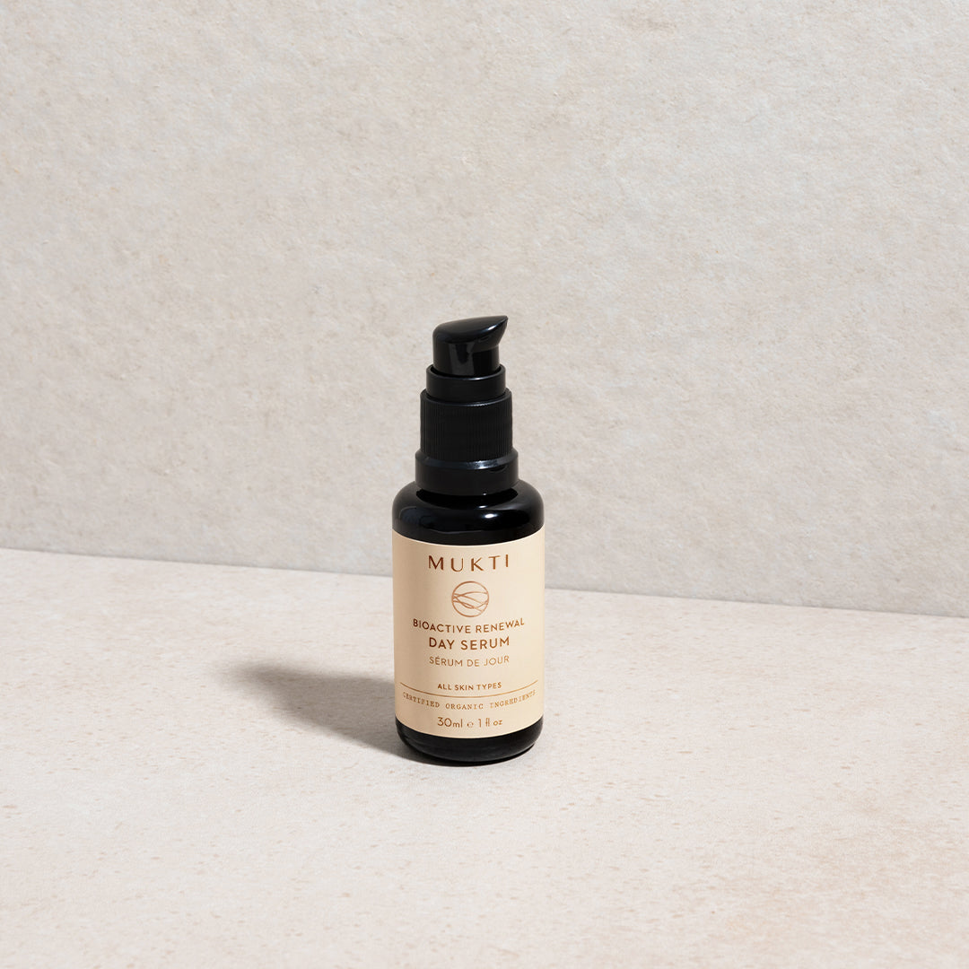 Mukti Organics | Bioactive Renewal Day Serum | Lifestyle Image - black pump bottle with beige label on a light beige background