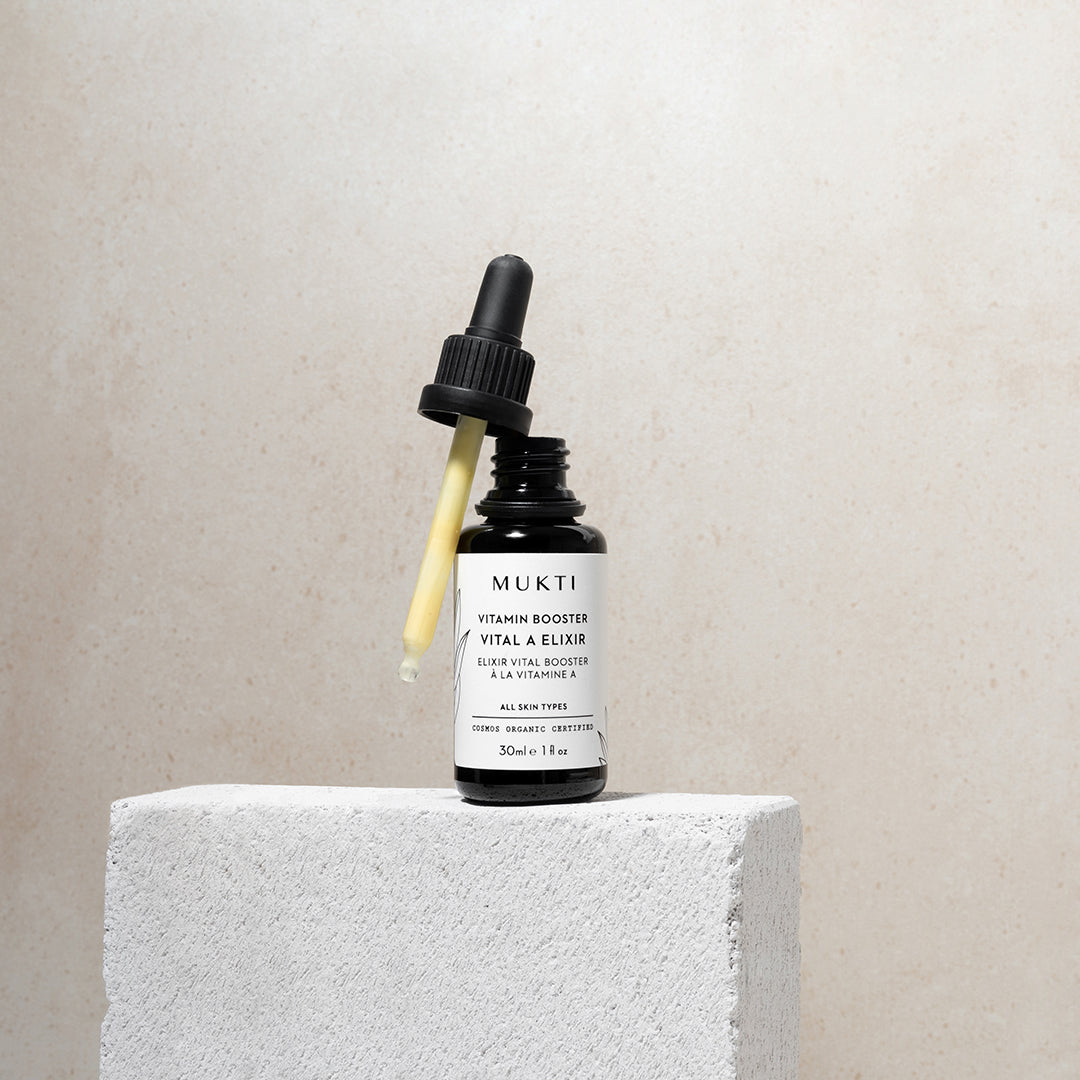 Mukti Organics | Vitamin Booster Vital A Elixir | Lifestyle Image - black dropper bottle open on a white stone block against a beige background