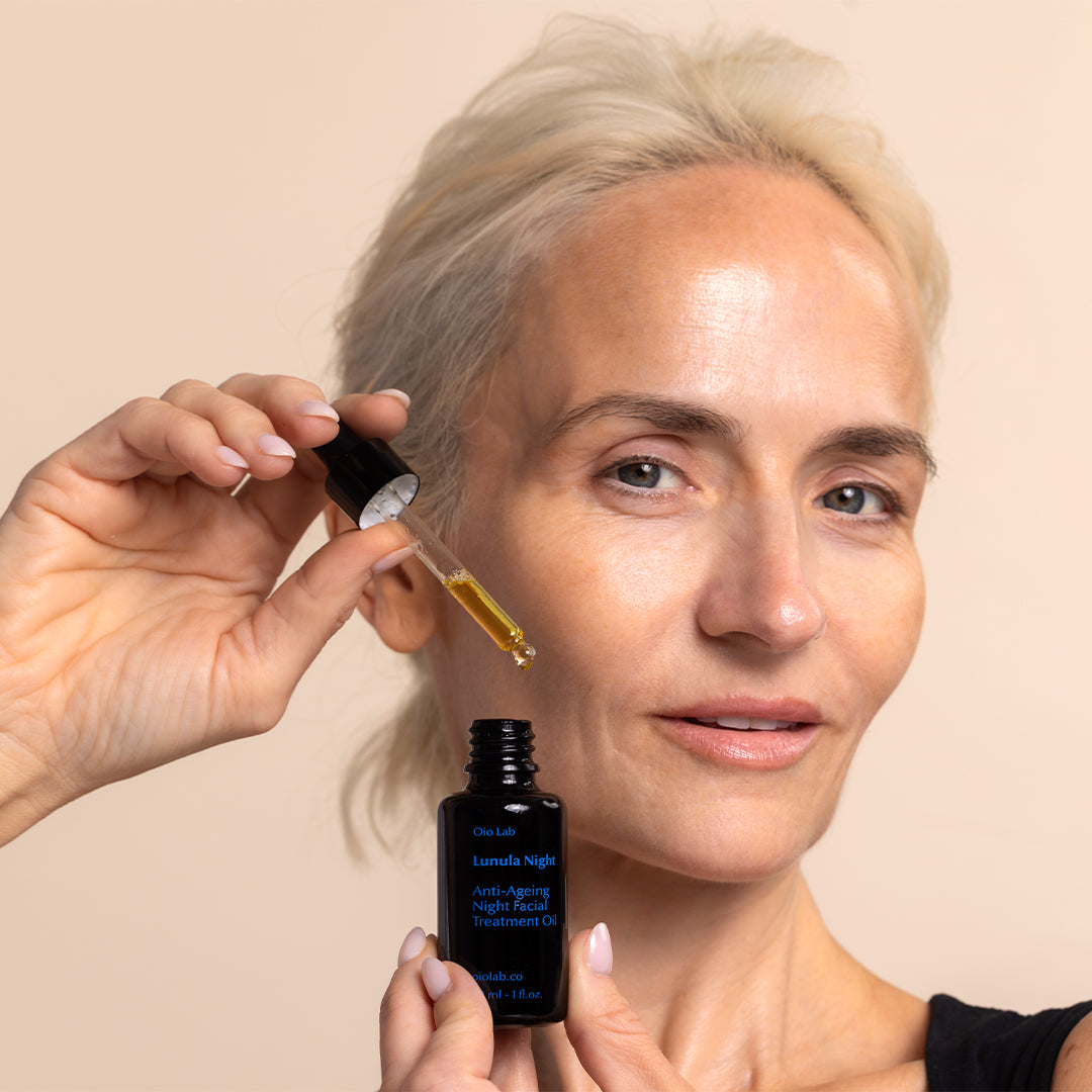 Oio Lab | Lunula Night Facial Treatment Oil | Model Image - woman holding facial oil bottle with dropper