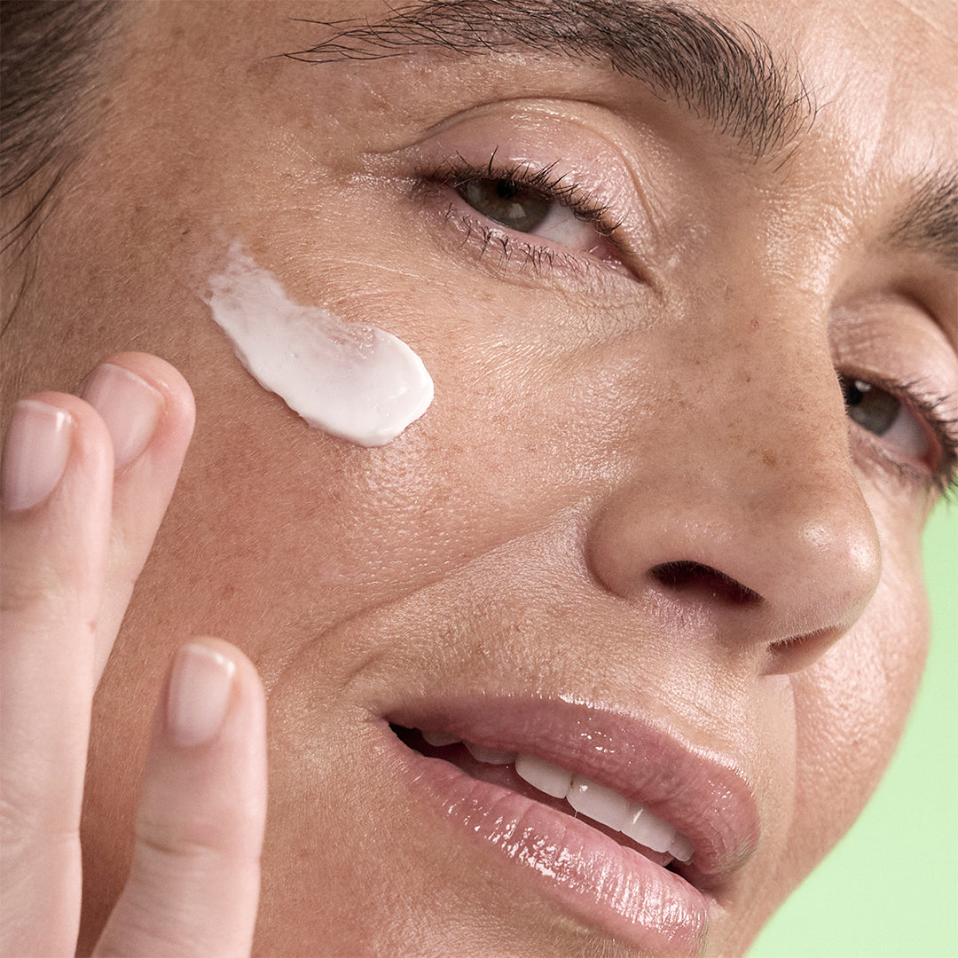 Pai Skincare | Age Confidence PDRN Revival Moisturizer | Model Image - close-up of a woman applying white moisturizer to her cheek with her fingertips