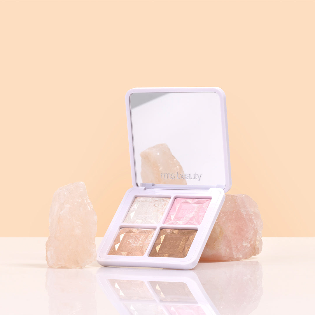 RMS Beauty | ReDimension Daily Glow Palette | Styled Image_Aug26  - open palette displayed with four shimmer shades and mirror, styled between rose quartz stones on a light peach background