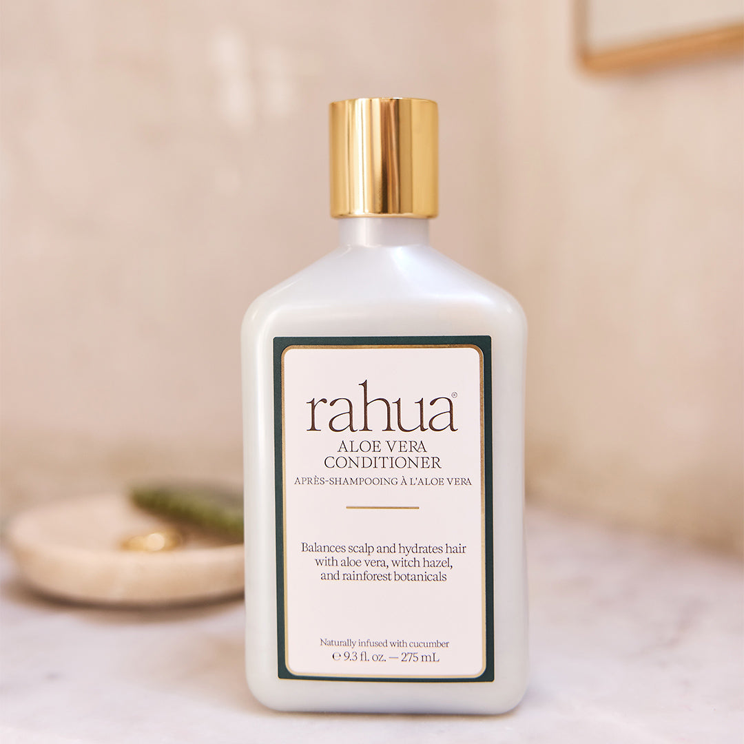 Rahua | Aloe Vera Conditioner | Lifestyle Image - white bottle with a gold cap on a bathroom counter