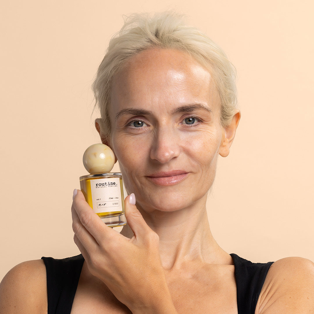 Routine | Natural Perfume Volume  #1 | Model Image, model holding perfume bottle against peach background