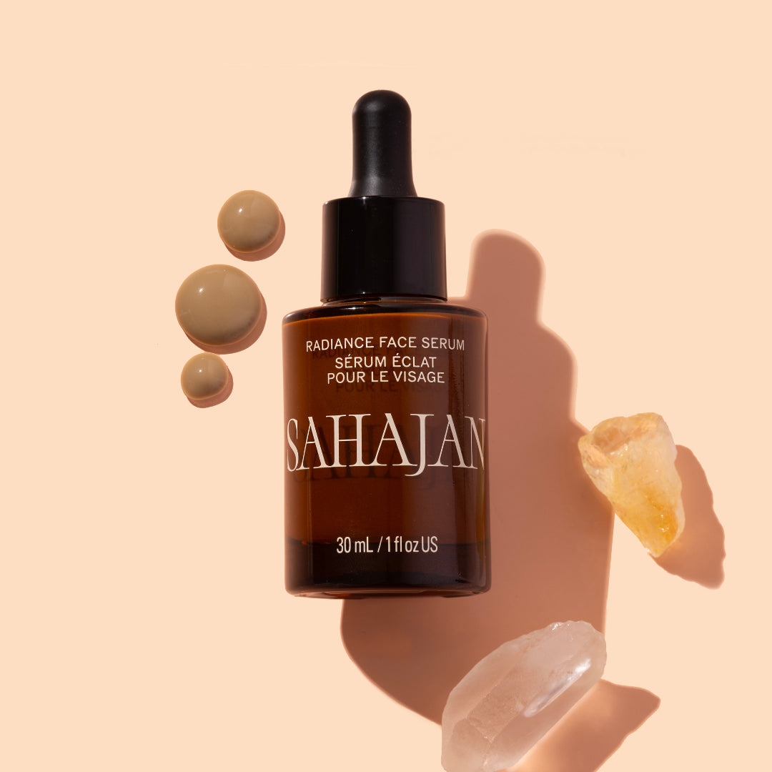 Sahajan | Radiance Face Serum | Styled Image with Swatch - dropper bottle styled with serum droplets and crystal stones on a beige background