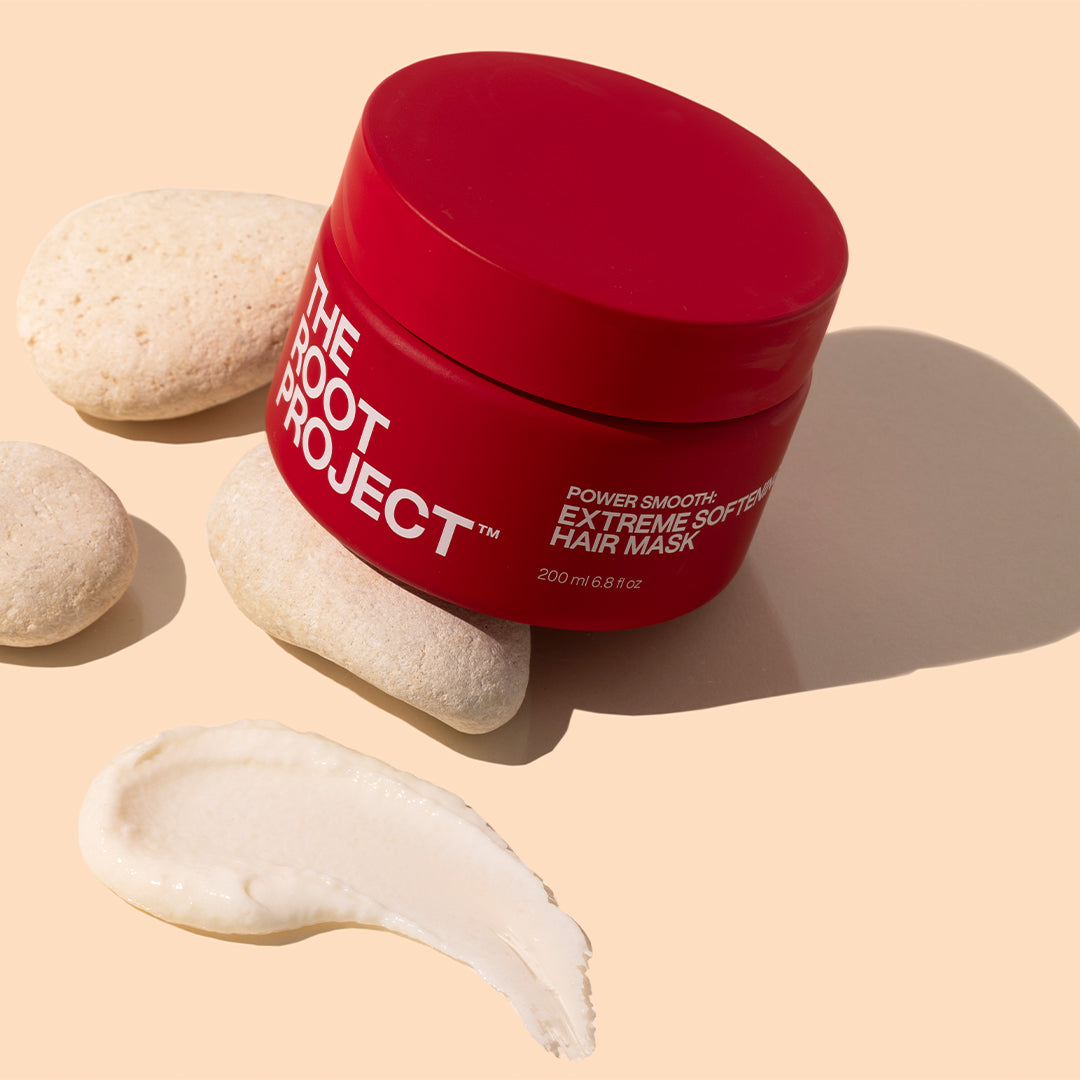The Root Project | Power Smooth Extreme Softening Hair Mask | Styled Image with Swatch_Oct26 - bright red jar with white lettering, cream-colored stones, and an ivory product swatch against a warm peach background