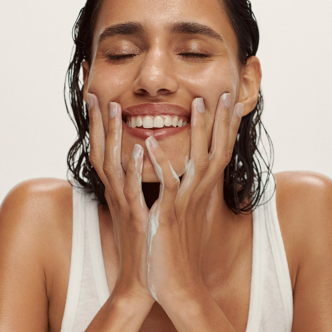 True Botanicals | Spirulina Cleansing Powder | Model Image2 - woman cleansing her face against a white background