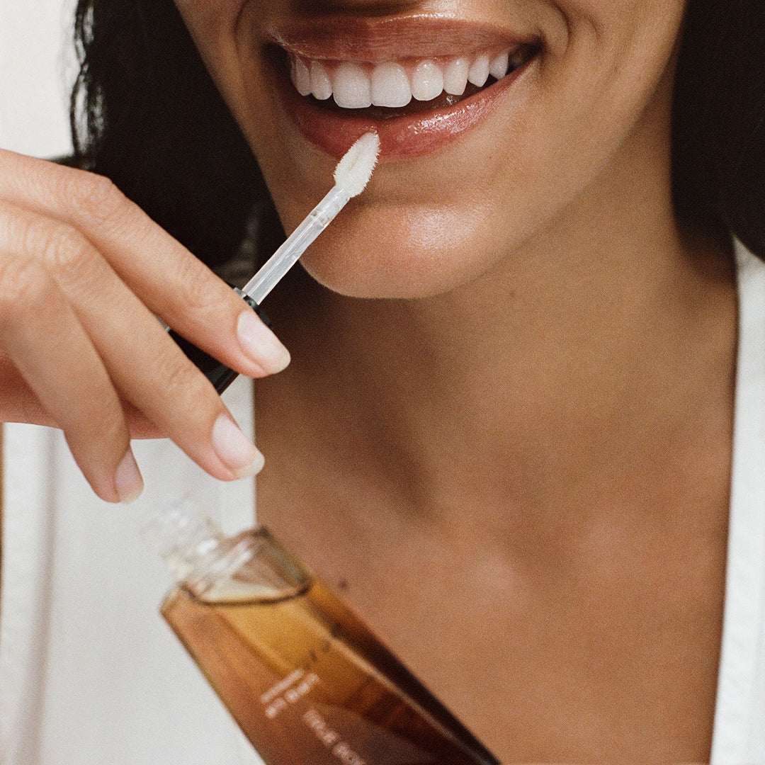 True Botanicals | Stocking Stuffer Best Sellers Lip Duo | Model Image - model applying lip treatment to her lips with a doe-foot applicator