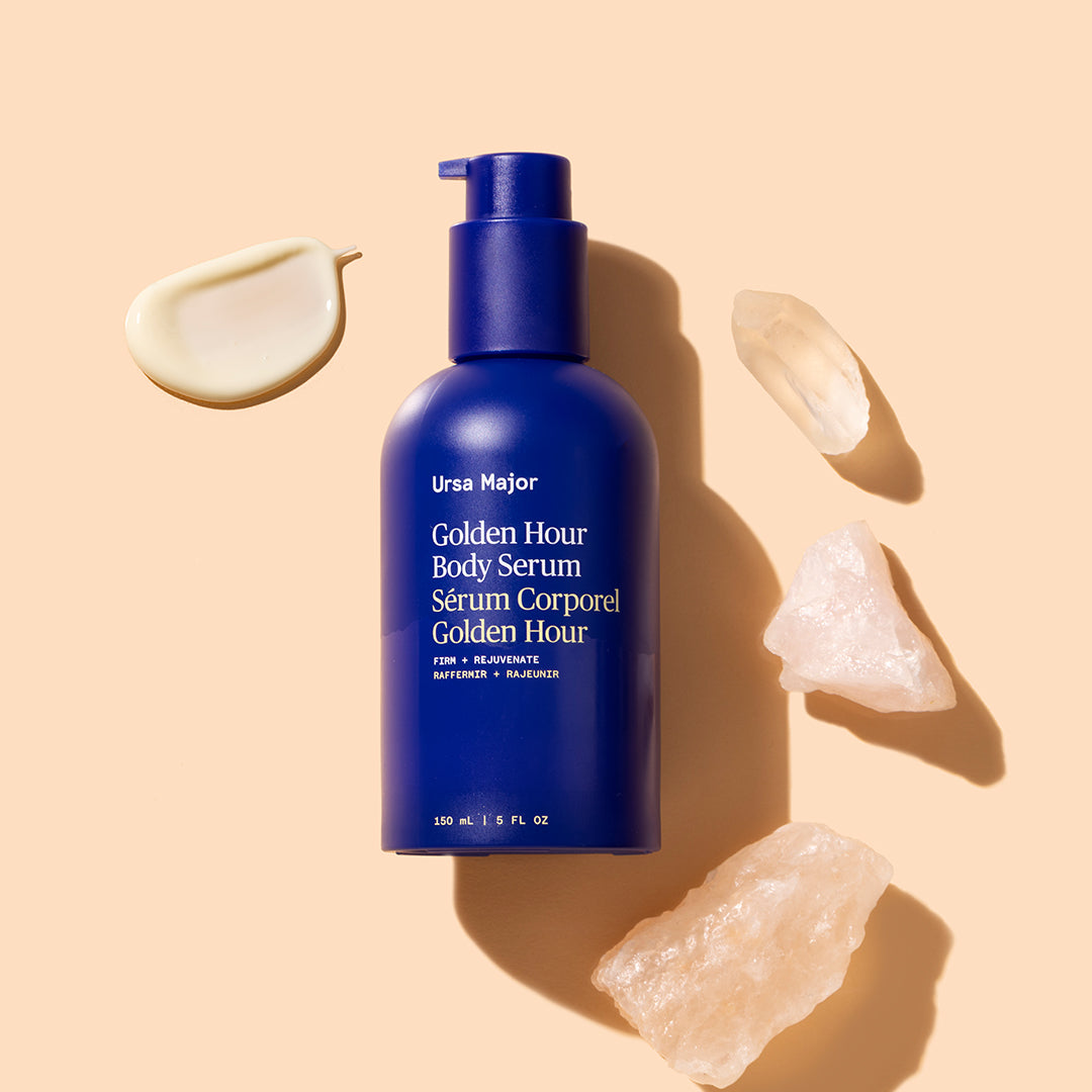 Ursa Major | Golden Hour Body Serum | Product Image with Swatch - blue pump bottle with cream swatch and crystal accents on neutral background