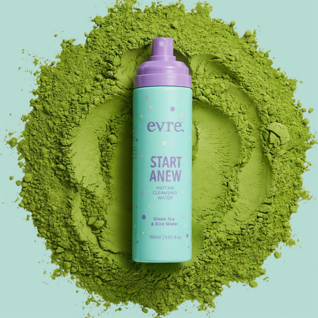 evre. | Start Anew Matcha Cleansing Water | Lifestyle Image - aqua bottle with purple pump surrounded by green matcha powder on a light aqua background background