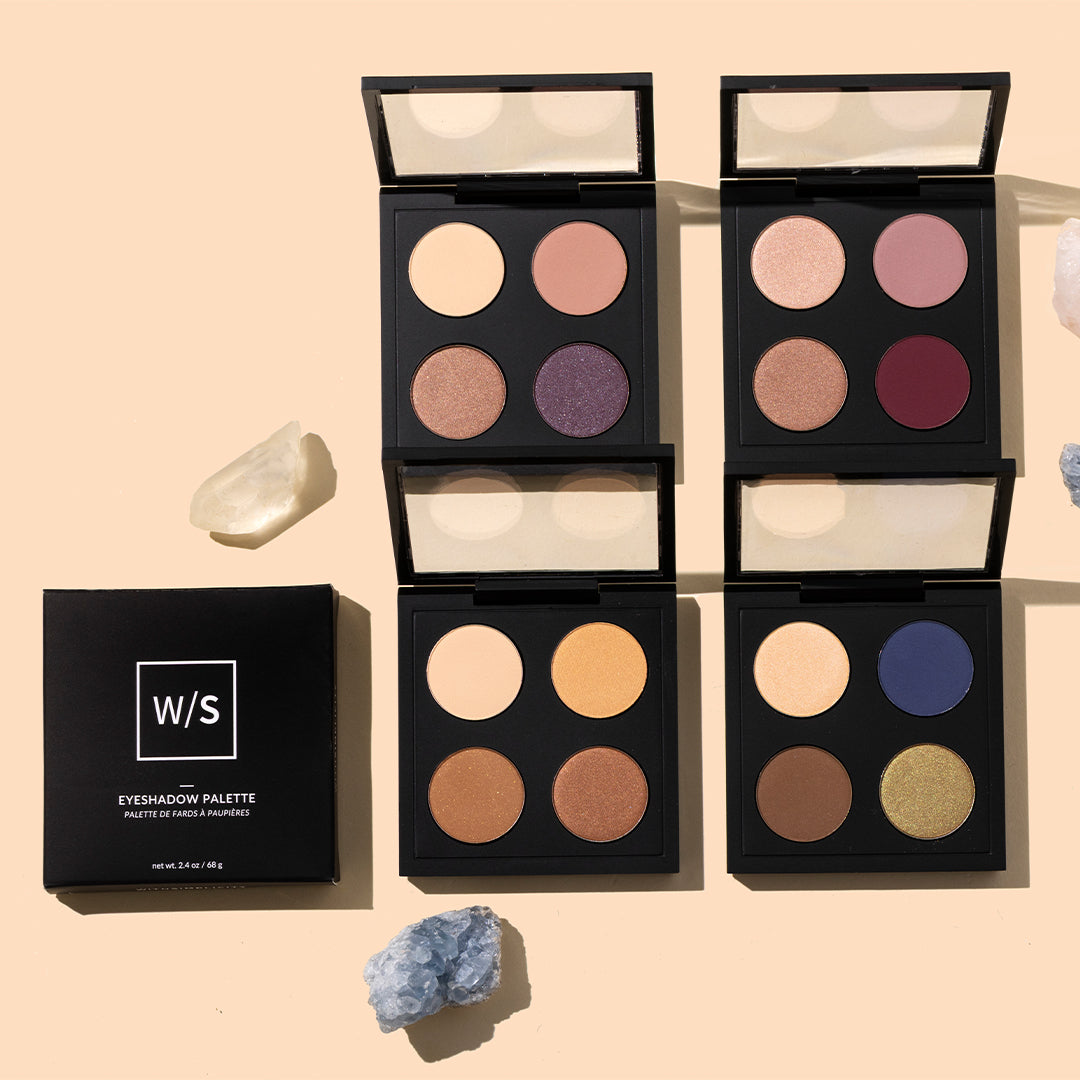 withSimplicity | Color Theory Eye Palettes | Styled Image with Swatch_Sep26 - eyeshadow palette with four open black compacts displaying neutral and colorful shades on peach background with stone accents