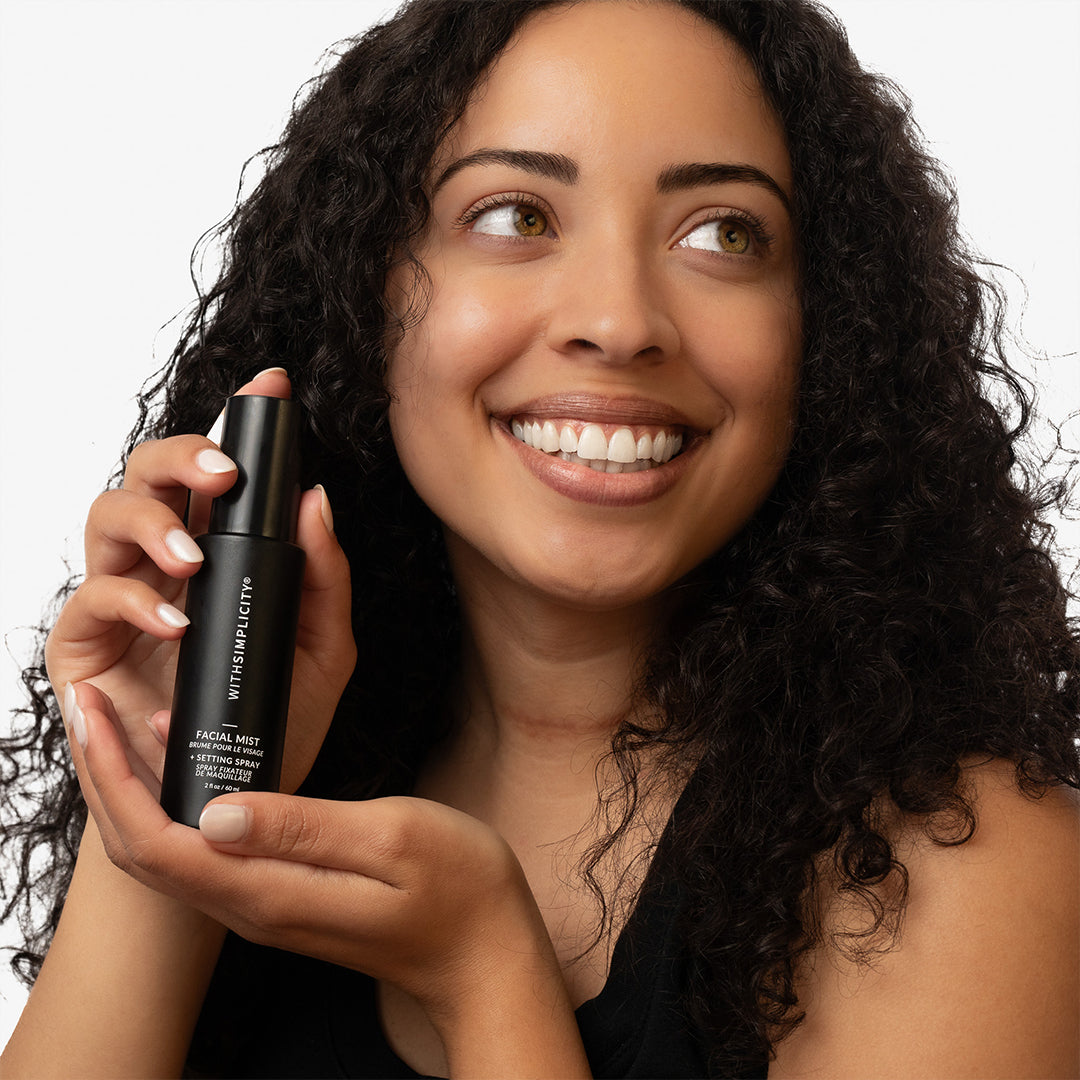 withSimplicity | Facial Mist + Setting Spray | Model Image - model holding spray bottle against a white background